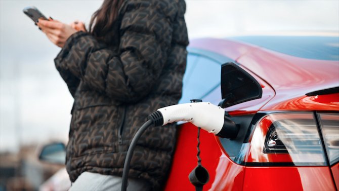 woman-using-smartphone-near-charging-electric-car-2023-04-07-16-09-11-utc.jpg