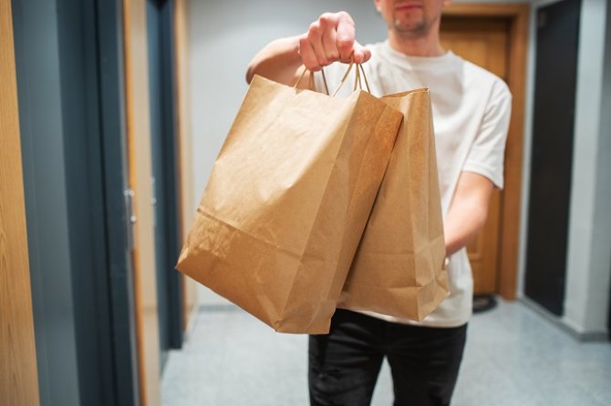 delivery-man-holding-paper-bag-with-food-in-the-en-2022-12-23-04-11-39-utc.jpg